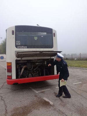 Policjant sprawdza pracę silnika autobusu.