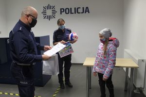 Policjanci wręczają dziewczynce paczki z upominkami