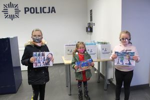 Trójka dzieci prezentuje prace ułożone z puzzli na konkurs